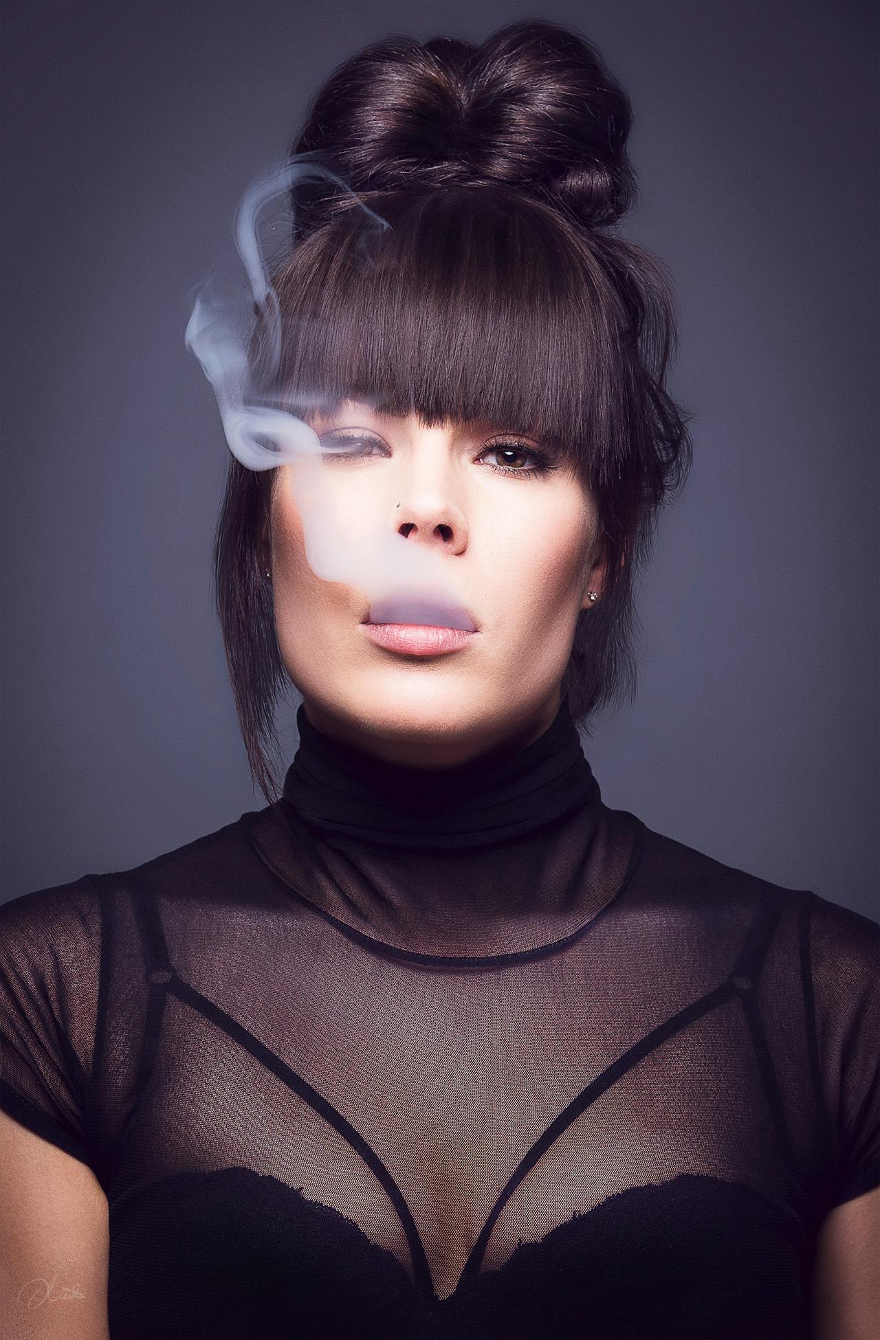 A portrait of a woman exhaling vapor